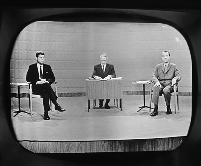 FILE - In this Sept. 26, 1960 file photo, moderator Howard K. Smith sits between, Sen. John Kennedy, left, and Vice President Richard Nixon as they appear on television studio monitor set during  their debate in Chicago.  The Kennedy image, the "mystique" that attracts tourists and historians alike, did not begin with his presidency and is in no danger of ending 50 years after his death. The multimedia story began in childhood with newsreels and newspaper coverage of the smiling Kennedy brood, and it continued with books, photographs, movies and finally television, notably the telegenic JFK’s presidential debates with Nixon. (AP Photo)